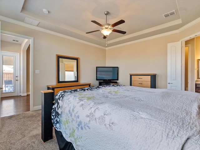 carpeted bedroom featuring a tray ceiling, ceiling fan, and crown molding