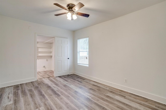 unfurnished bedroom featuring a walk in closet, ceiling fan, a closet, and light hardwood / wood-style floors