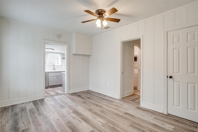 spare room featuring light hardwood / wood-style flooring, ceiling fan, ornamental molding, and sink