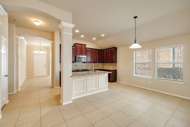 kitchen featuring tasteful backsplash, light stone counters, vaulted ceiling, light tile patterned floors, and decorative light fixtures