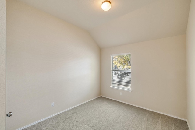 carpeted spare room featuring vaulted ceiling