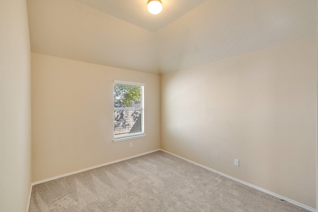 empty room with light colored carpet and lofted ceiling