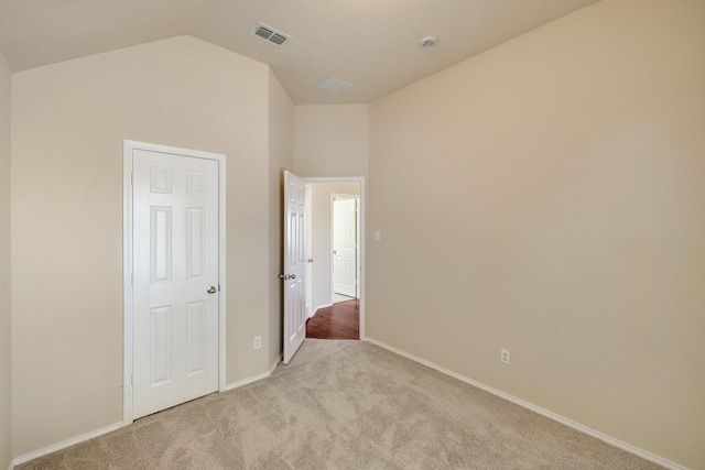 unfurnished bedroom featuring light colored carpet and vaulted ceiling