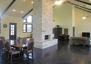 dining area featuring a stone fireplace, ceiling fan, beamed ceiling, and high vaulted ceiling