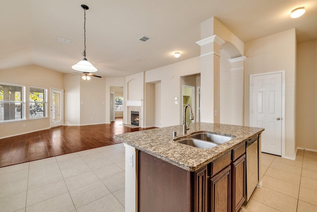 kitchen featuring dishwasher, sink, hanging light fixtures, light stone countertops, and light wood-type flooring