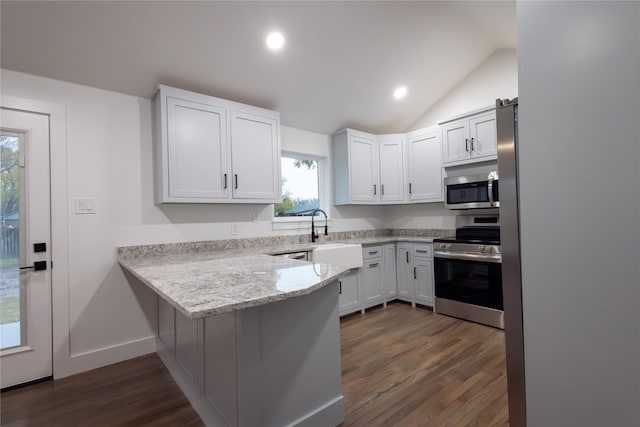 kitchen featuring kitchen peninsula, appliances with stainless steel finishes, dark hardwood / wood-style flooring, white cabinetry, and lofted ceiling