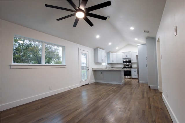 unfurnished living room with ceiling fan, sink, lofted ceiling, and dark wood-type flooring