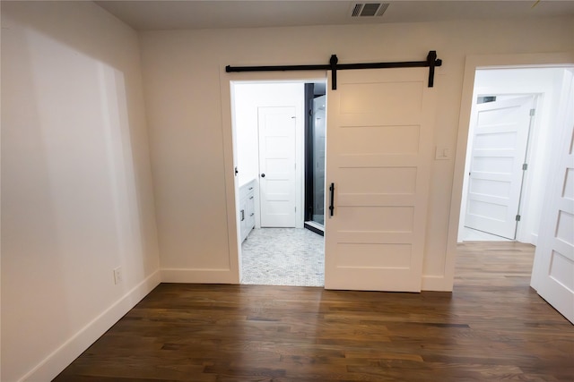 spare room with a barn door and dark wood-type flooring