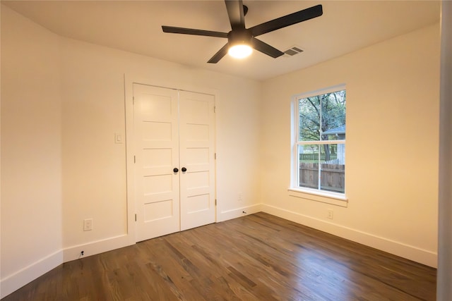 unfurnished bedroom featuring ceiling fan, a closet, and dark wood-type flooring