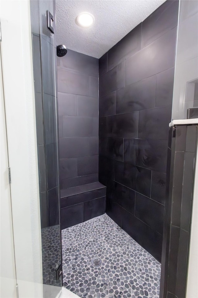 bathroom with a textured ceiling and a shower with shower door