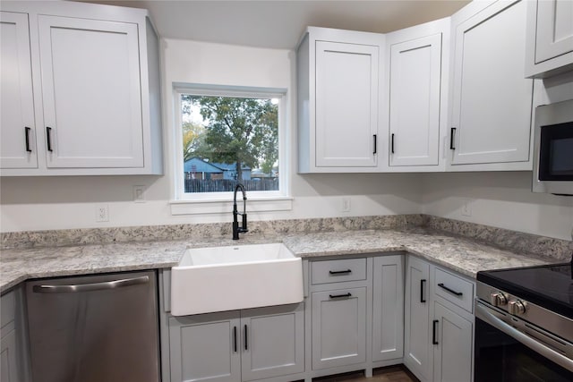 kitchen with light stone countertops, appliances with stainless steel finishes, white cabinetry, and sink