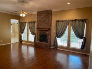 unfurnished living room featuring dark hardwood / wood-style flooring, a brick fireplace, ceiling fan, and crown molding