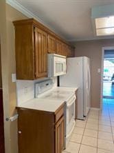 kitchen featuring crown molding, light tile patterned floors, and white appliances