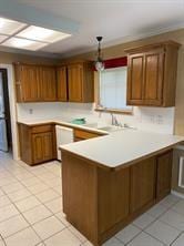 kitchen with kitchen peninsula, pendant lighting, white dishwasher, and light tile patterned floors