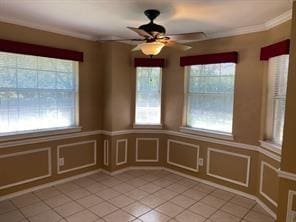 unfurnished dining area featuring ceiling fan, a healthy amount of sunlight, light tile patterned flooring, and ornamental molding