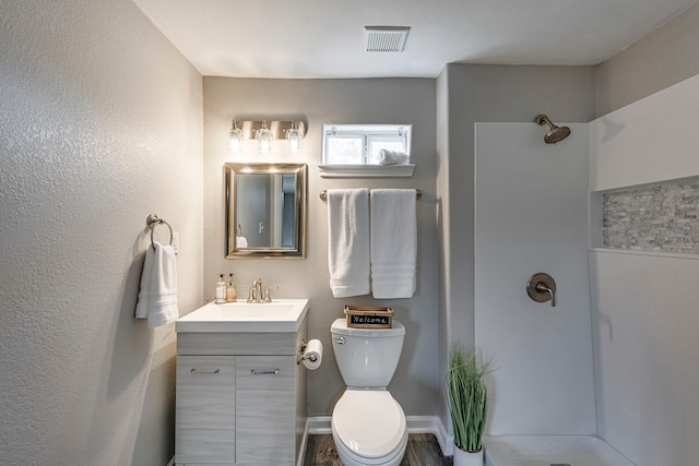 bathroom with walk in shower, vanity, and toilet