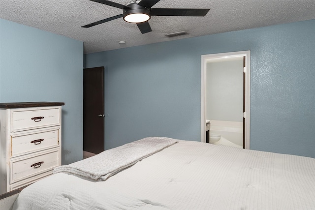 bedroom featuring ceiling fan, ensuite bathroom, and a textured ceiling