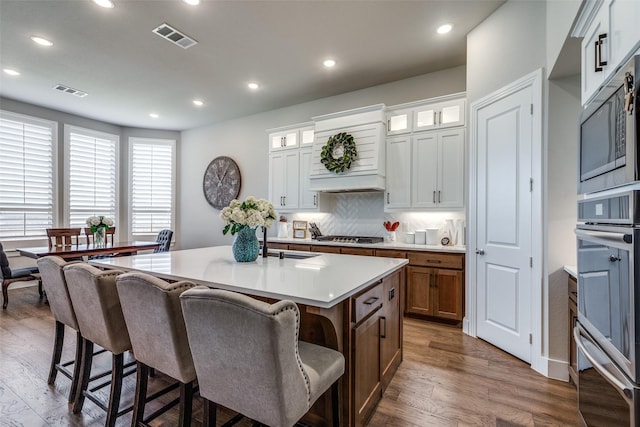 kitchen featuring backsplash, a kitchen island with sink, sink, white cabinets, and dark hardwood / wood-style floors