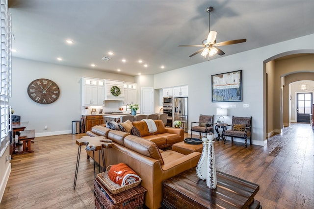 living room featuring ceiling fan, wood-type flooring, and sink