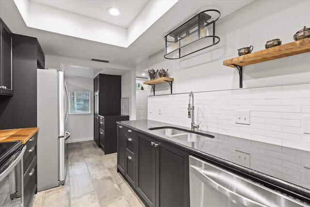 kitchen with appliances with stainless steel finishes, tasteful backsplash, a raised ceiling, and sink