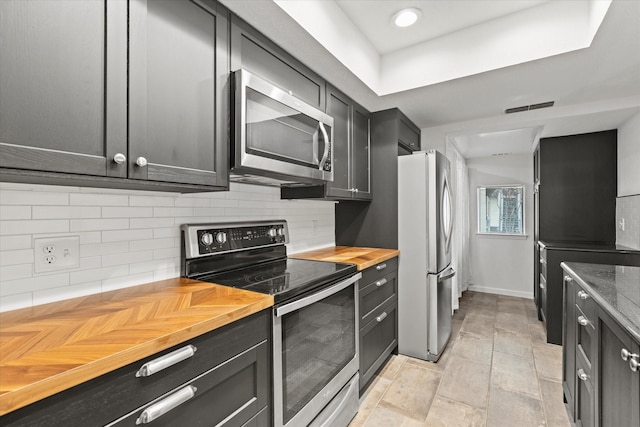 kitchen with butcher block counters, decorative backsplash, and appliances with stainless steel finishes