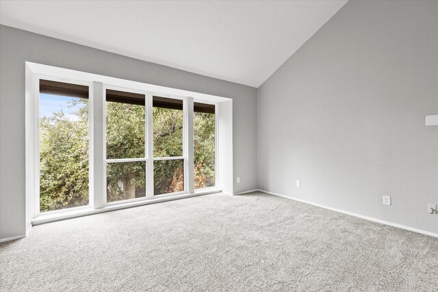 carpeted empty room featuring vaulted ceiling