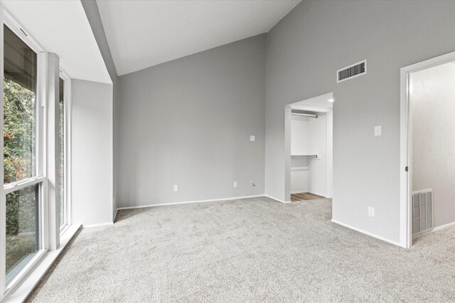 carpeted empty room featuring high vaulted ceiling