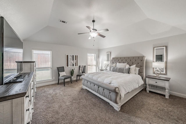 carpeted bedroom with multiple windows, vaulted ceiling, a raised ceiling, and ceiling fan