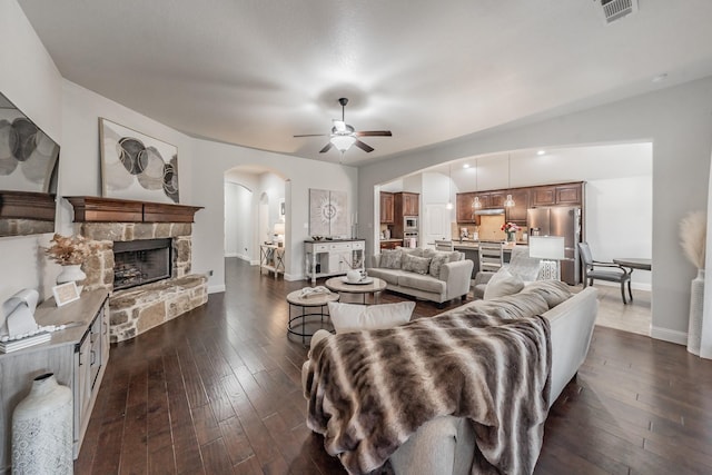 living room featuring ceiling fan, a fireplace, and dark hardwood / wood-style floors