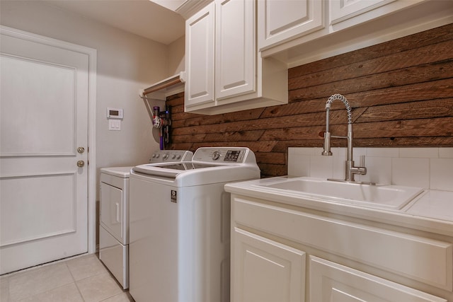 clothes washing area featuring washing machine and clothes dryer, sink, light tile patterned flooring, and cabinets