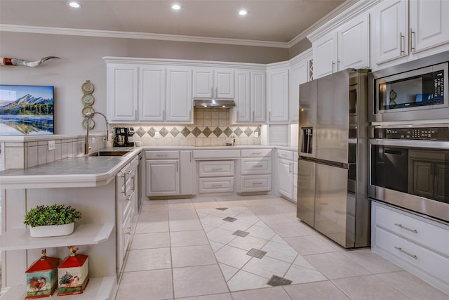 kitchen with ornamental molding, stainless steel appliances, sink, light tile patterned floors, and white cabinetry