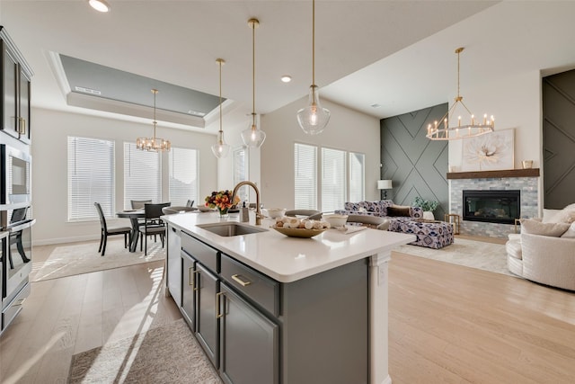 kitchen featuring pendant lighting, a center island with sink, sink, light hardwood / wood-style flooring, and appliances with stainless steel finishes