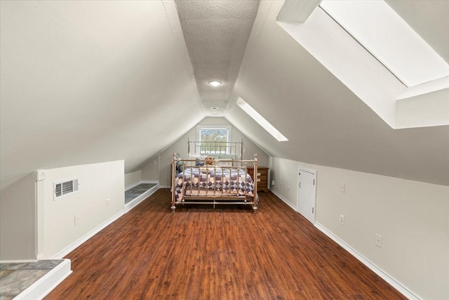 unfurnished bedroom featuring a textured ceiling, dark wood-type flooring, and vaulted ceiling with skylight