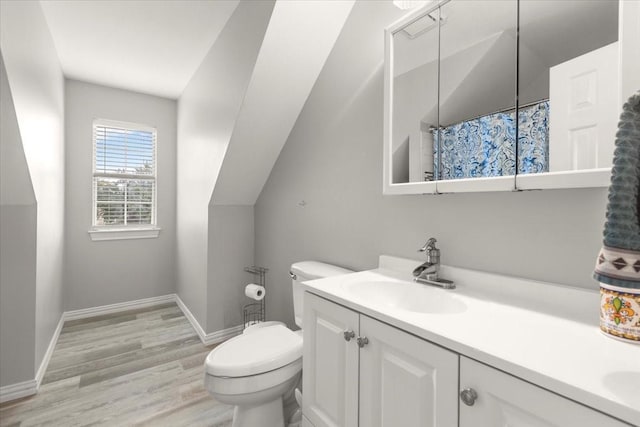 bathroom with hardwood / wood-style floors, curtained shower, lofted ceiling, vanity, and toilet