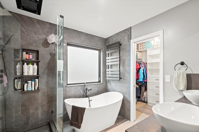 bathroom featuring shower with separate bathtub, radiator, sink, and tile walls