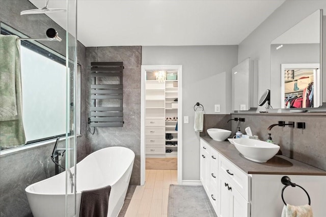 bathroom featuring backsplash, radiator heating unit, vanity, a bath, and wood-type flooring