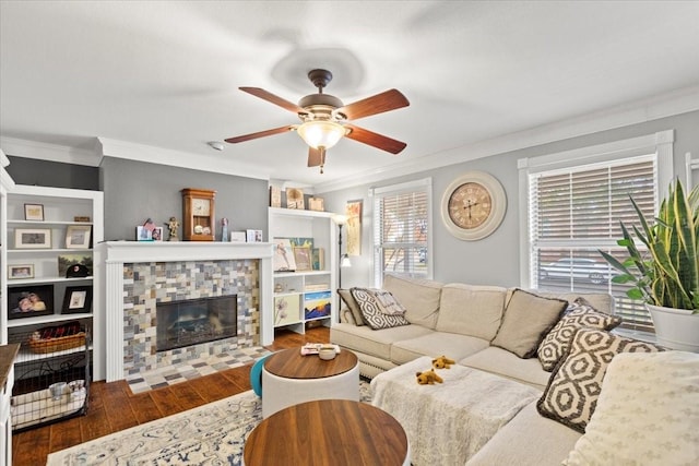 living room featuring hardwood / wood-style flooring, a tile fireplace, ornamental molding, and ceiling fan