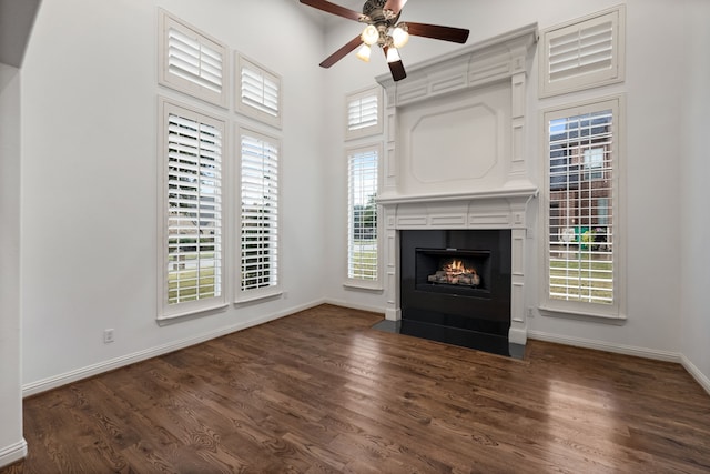 unfurnished living room featuring a towering ceiling, dark hardwood / wood-style floors, and ceiling fan