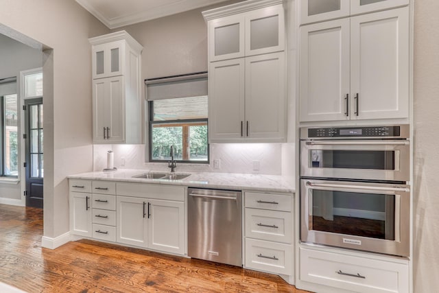 kitchen with white cabinets, appliances with stainless steel finishes, a wealth of natural light, and crown molding