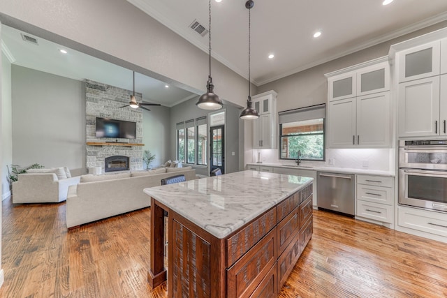 kitchen featuring light stone countertops, stainless steel appliances, sink, white cabinets, and a kitchen island