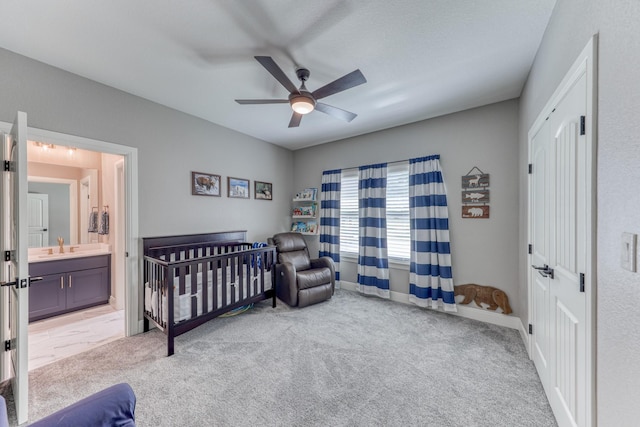 bedroom featuring ensuite bath, ceiling fan, sink, light carpet, and a crib