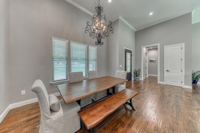 dining room with a chandelier, a towering ceiling, hardwood / wood-style flooring, and crown molding