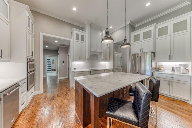 kitchen featuring appliances with stainless steel finishes, tasteful backsplash, pendant lighting, light hardwood / wood-style floors, and a kitchen island