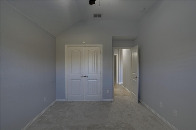 unfurnished bedroom featuring a closet, ceiling fan, vaulted ceiling, and light colored carpet