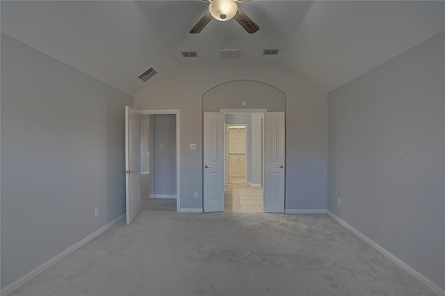 unfurnished bedroom with ceiling fan, vaulted ceiling, ensuite bath, and light colored carpet