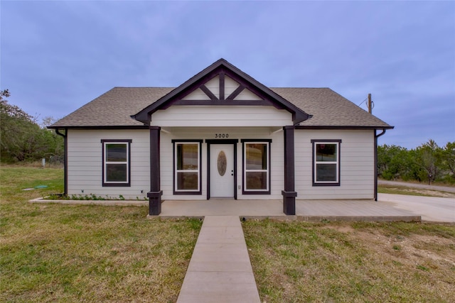 bungalow-style home with covered porch and a front lawn