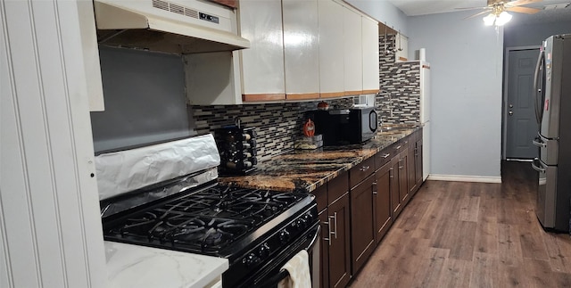 kitchen with black appliances, dark stone countertops, tasteful backsplash, dark brown cabinets, and wood-type flooring