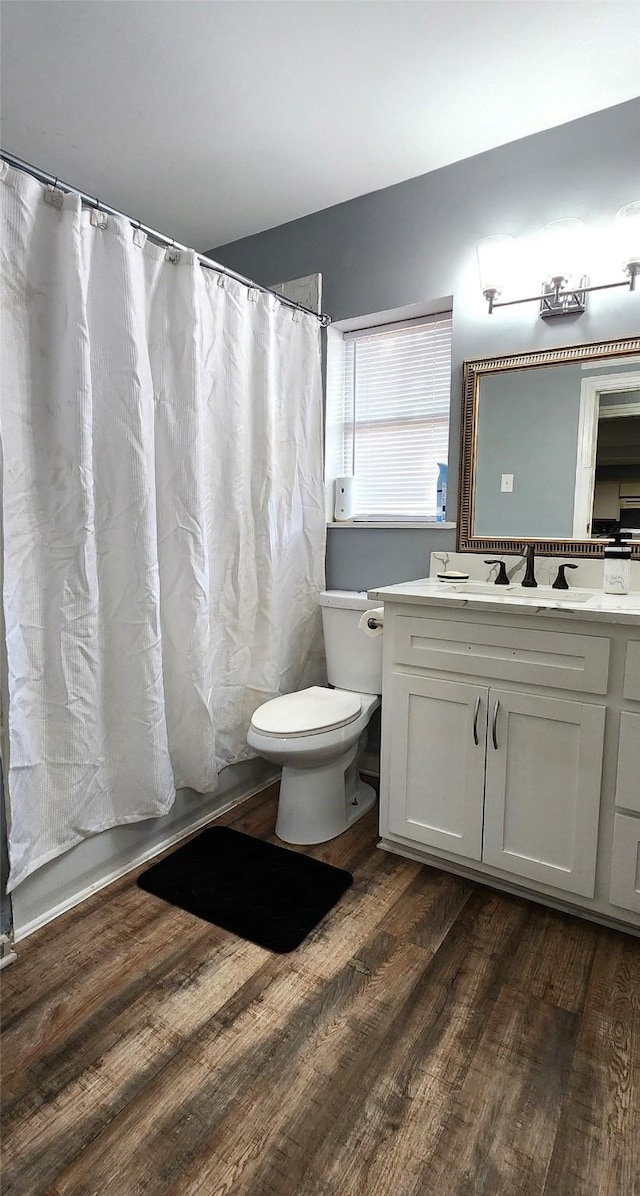 full bathroom featuring hardwood / wood-style floors, vanity, shower / tub combo, and toilet