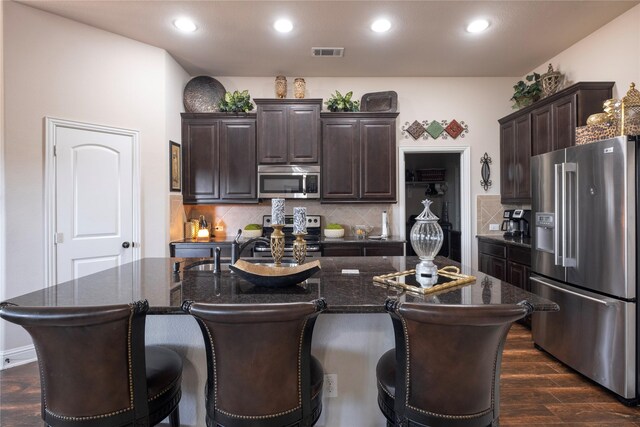 kitchen featuring backsplash, dark brown cabinetry, stainless steel appliances, sink, and dark hardwood / wood-style floors