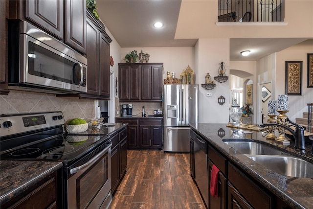 kitchen featuring stainless steel appliances, a towering ceiling, an island with sink, a kitchen bar, and hardwood / wood-style flooring